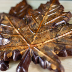 A dark chocolate maple leaf colored with autumn gold and orange colors. Rustic looking, edible.