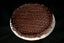 Round Chocolate Oblivion Torte with a glossy quenelle-patterned ganache top and dripping edges, on a white board.