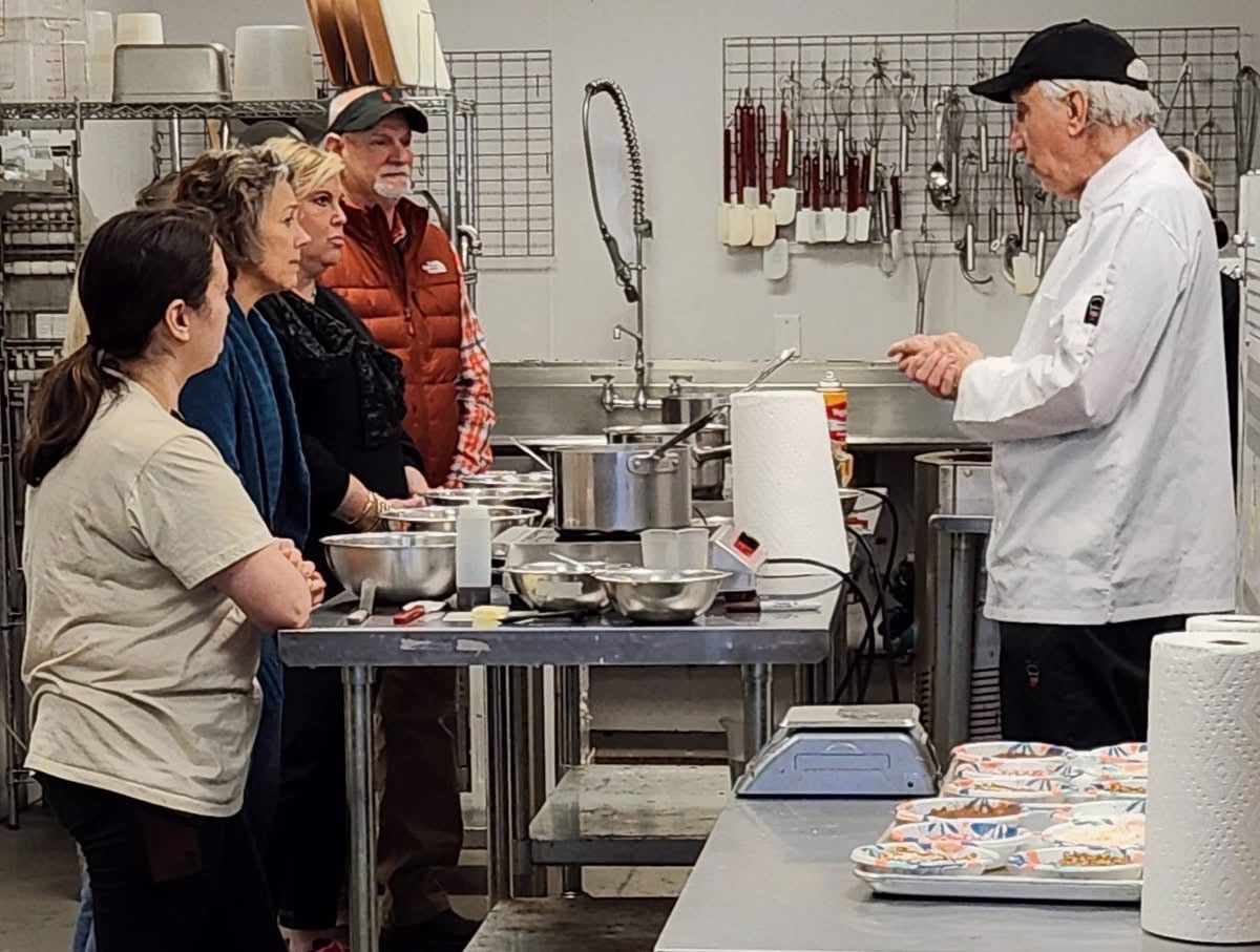 Chef Bill Dietz instructing participants during a chocolate tempering workshop at The Secret Chocolatier, guiding them through the process in a hands-on learning environment.