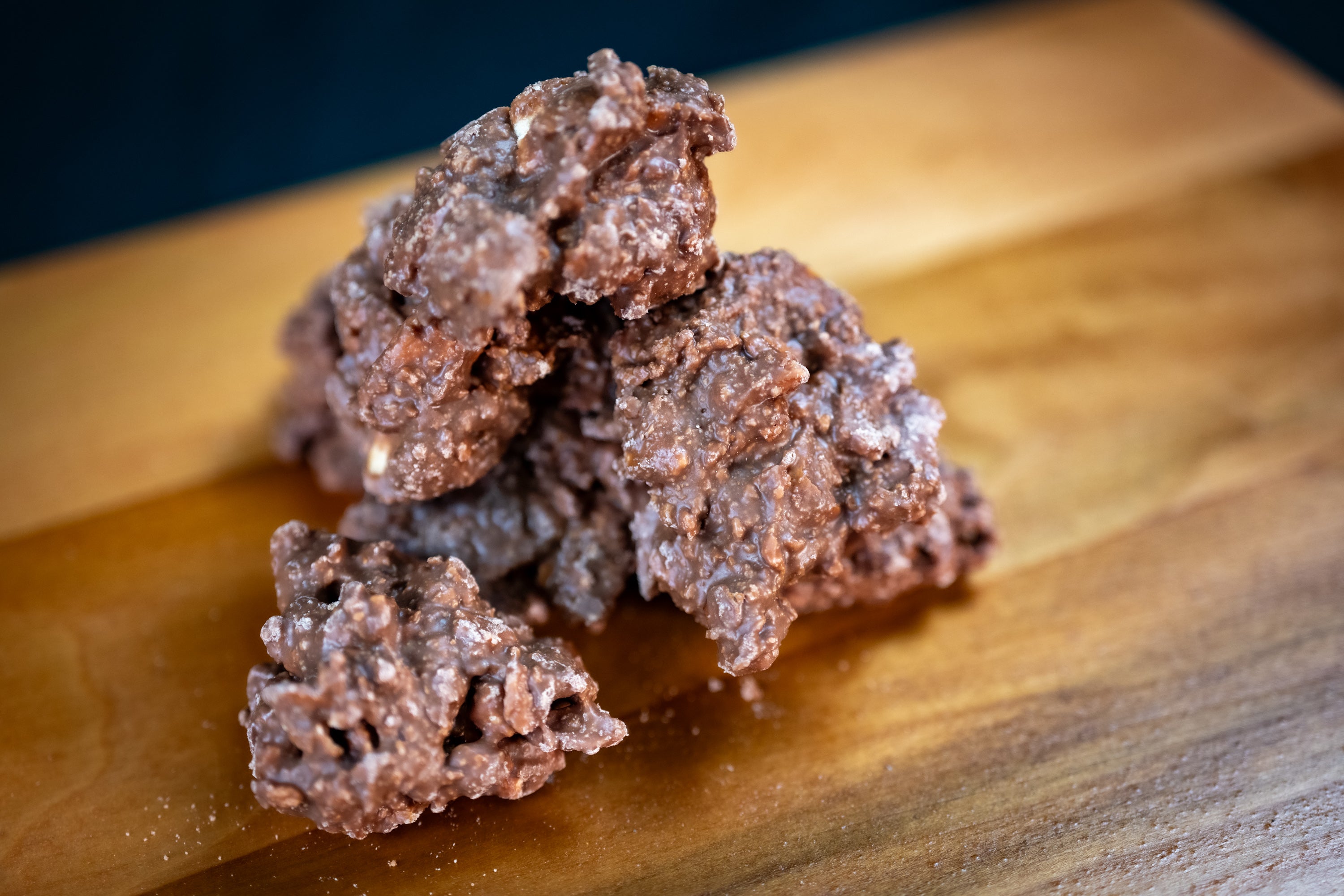 Close-up of bite-sized milk chocolate pretzel clusters on a wooden board, showing texture and crunch.