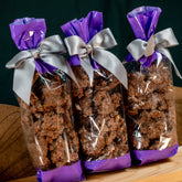 Three gift bags of Milk Chocolate Pretzel Poppers tied with silver ribbons and purple wrap, perfect for gifting or snacking.