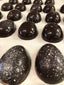 Dark chocolate Easter eggs hand-painted with white luster speckles, in two sizes — small halves and larger full eggs — on parchment paper.