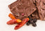 Blueberry Chili Chocolate Bark pieces with whole dried chili peppers and dried blueberries shown alongside the chocolate.