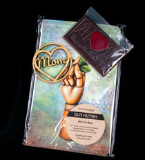 Mother's Day gift set — wooden 'Mom' heart ornament, a chocolate M bar with a red heart center, and a Duy Huynh 'Mint to Bee' notebook from Lark and Key.