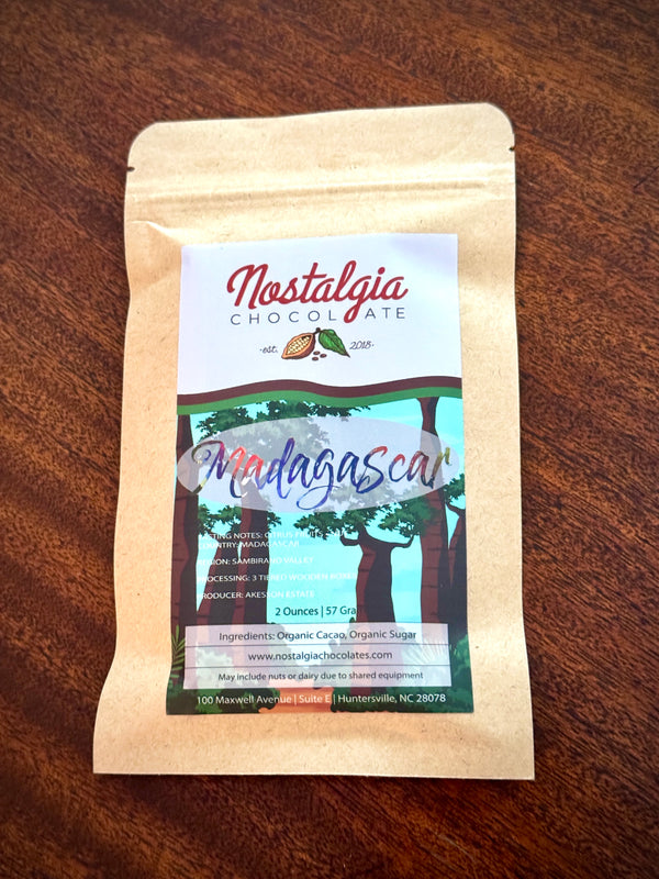 Nostalgia Chocolate Madagascar single-origin bar in a kraft-paper bag with a green forest-illustration label.
