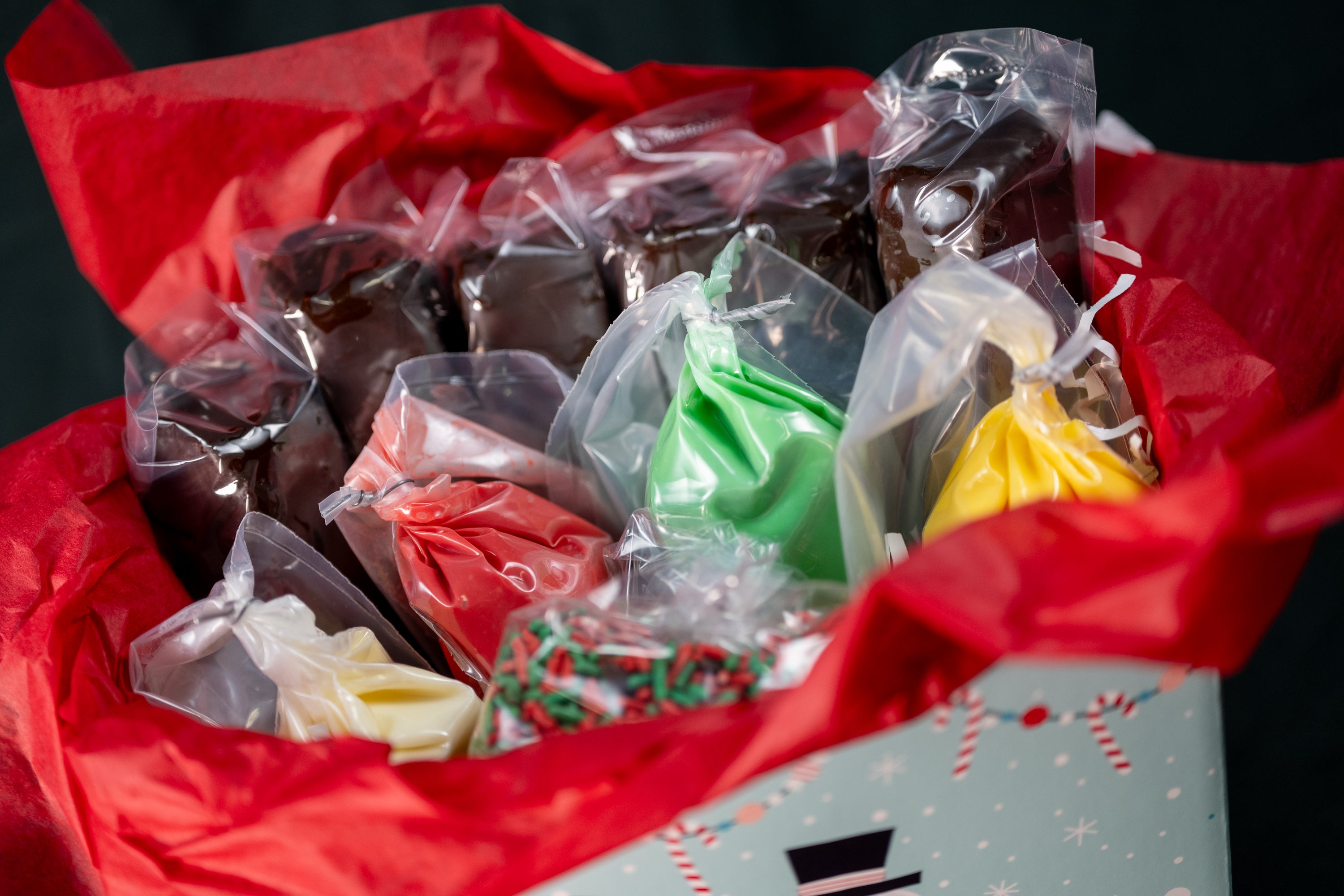 Brownie Pop Decorating Kit Christmas variant — open box showing brownie pops, red/green/yellow icing piping bags, and red/green sprinkles.
