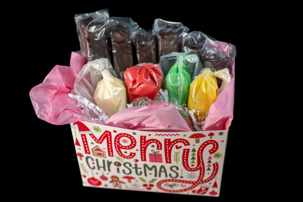 Brownie Pop Decorating Kit in a 'Merry Christmas' box — chocolate-coated brownie pops with piping bags of colored icing and decorations inside.