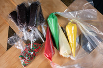 Brownie Pop Decorating Kit Christmas supplies — brownie pops on sticks, green/red/cream/yellow icing piping bags, and red/green sprinkles.
