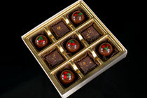 Dairy-Free Decadence sampler — nine pieces on a gold tray alternating hand-painted Candied Cherry Coconut Milk Caramel bon bons with square dark chocolate truffles finished in gold sprinkles.