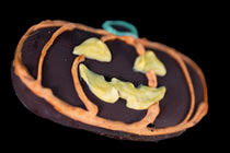 Chocolate-covered graham cracker jack-o'-lantern with hand-piped orange pumpkin ribs, a green stem, and a yellow jack-o'-lantern face.