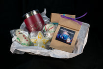 The Cozy Cocoa Collection gift basket — pink Secret Chocolatier tumbler, Hot Cocoa Dreams pouch, peppermint truffle ball, and hand-piped snowman and angel chocolates.