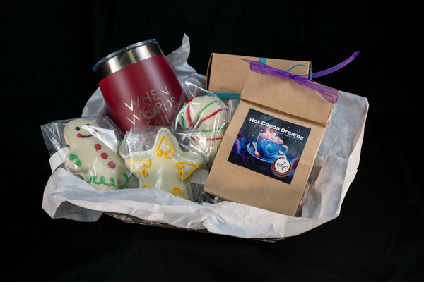 The Cozy Cocoa Collection gift basket — pink Secret Chocolatier tumbler, Hot Cocoa Dreams pouch, peppermint truffle ball, and hand-piped snowman and angel chocolates.