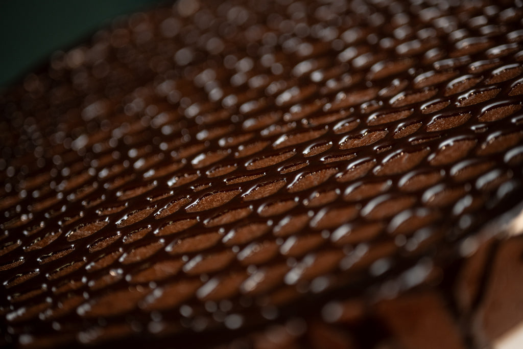 Macro view of the Chocolate Oblivion Torte's quenelle-patterned ganache surface.