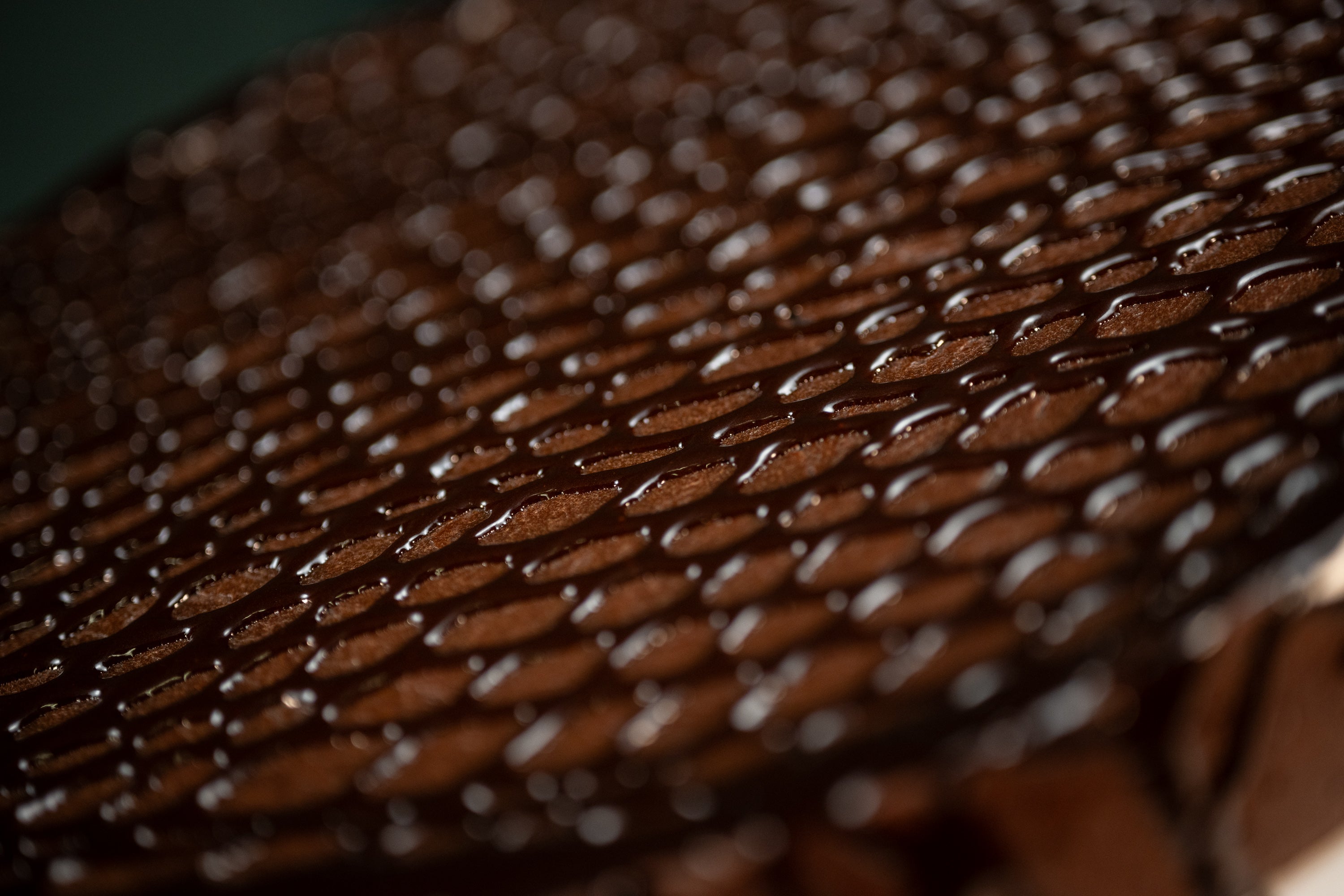 Macro view of the Chocolate Oblivion Torte's quenelle-patterned ganache surface.