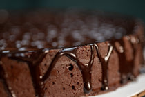 Side view of the Chocolate Oblivion Torte — dense chocolate cake with ganache poured over the top and dripping down the sides.