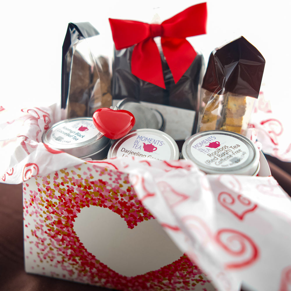 Tea & Chocolate Indulgence Kit Valentine's variant — heart-window box with chocolates, Moments In Tea tins, and a red heart ornament.