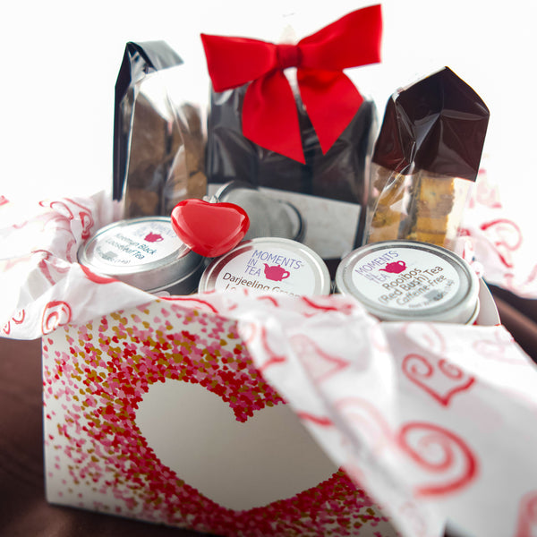 Tea & Chocolate Indulgence Kit Valentine's variant — heart-window box with chocolates, Moments In Tea tins, and a red heart ornament.