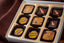 Adventurous Chocolate 9-piece box — bonbons with hand-painted decorative patterns in gold and red, featuring bold exotic flavors.