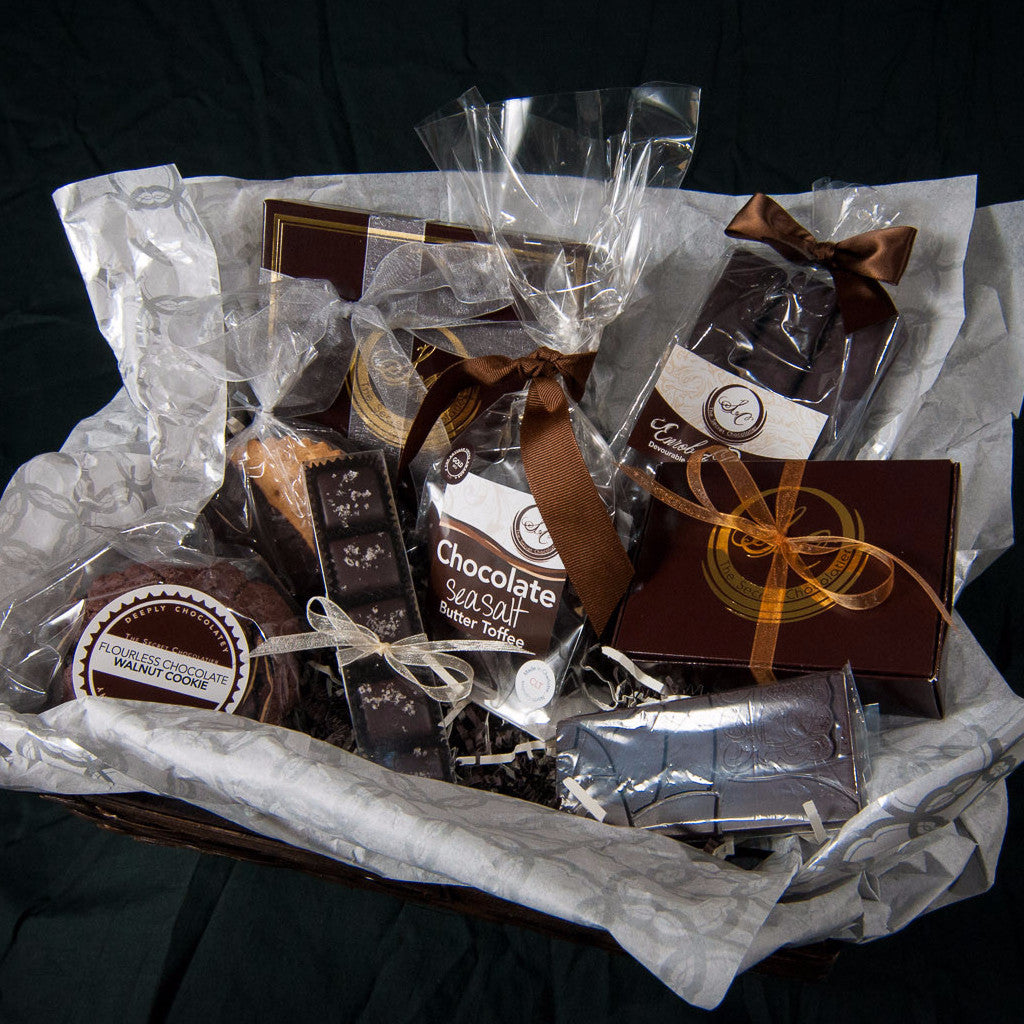 Overhead view of the Executive Chocolate Box gift basket, cellophane-wrapped TSC chocolates and confections tied with ribbons.