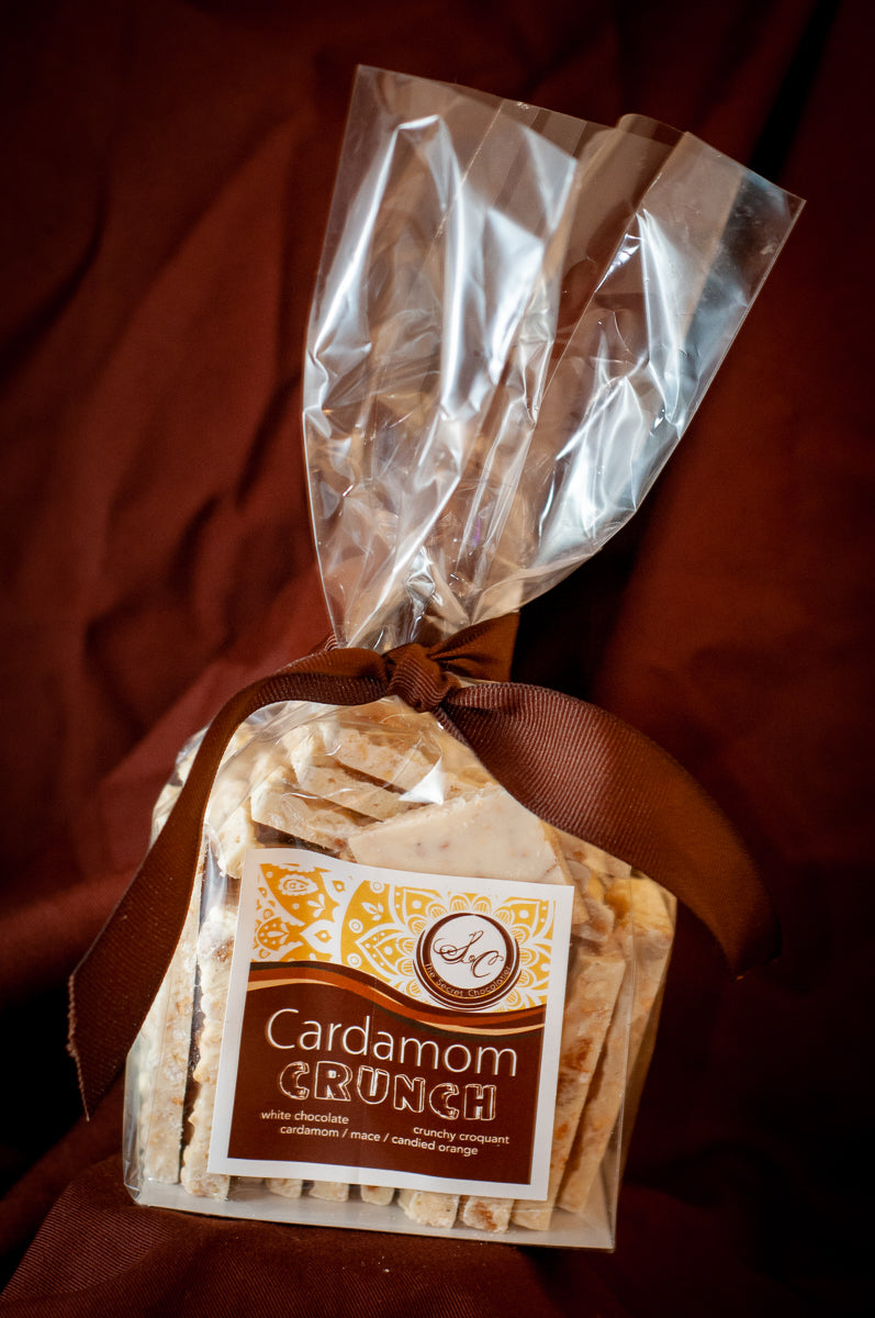 Close-up of Cardamom Crunch white chocolate showing the croquant and candied orange texture.