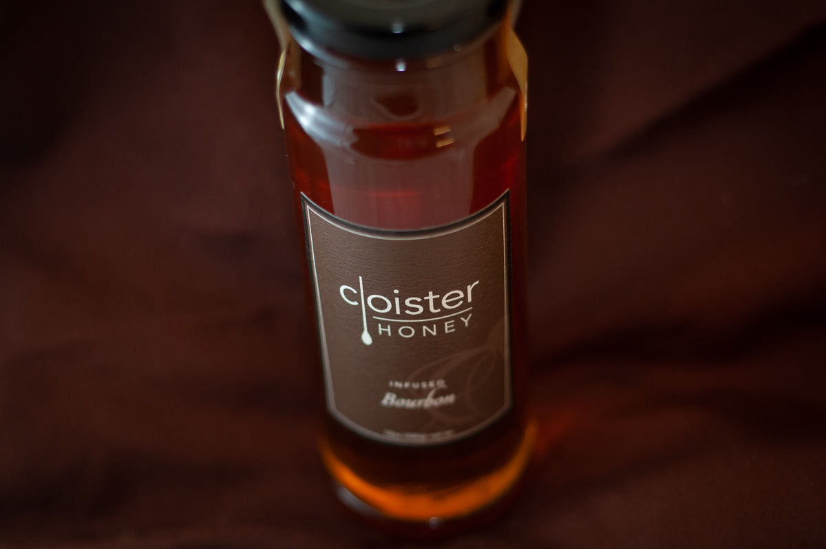 Cloister Honey Infused Bourbon Honey bottle with a brown label, on burgundy fabric.