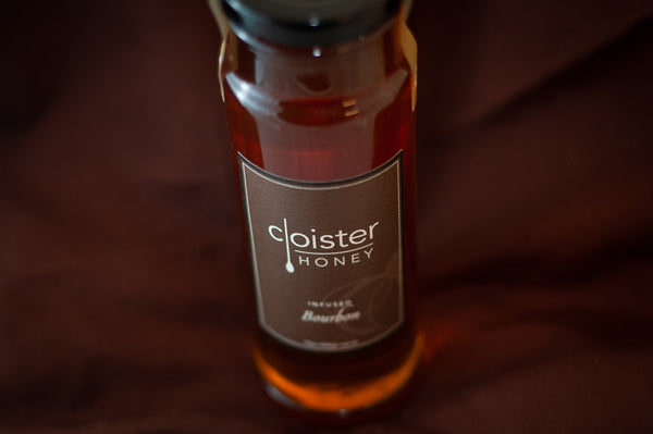 Cloister Honey Infused Bourbon Honey bottle with a brown label, on burgundy fabric.