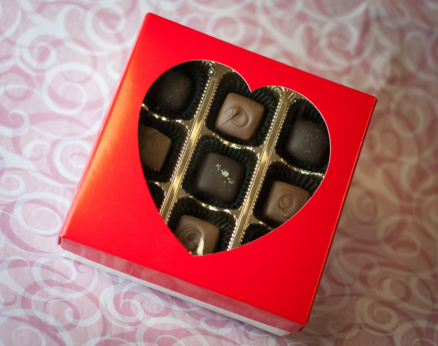 Valentine's Heart-Shaped Caramel Box — red gift box with heart cutout window showing dark chocolate caramels with sea salt inside.