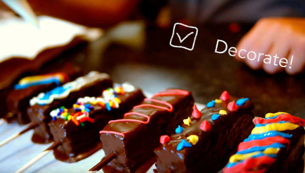Decorated Brownie Pop examples — chocolate-coated brownie pops finished with colorful icing piping and sprinkles.