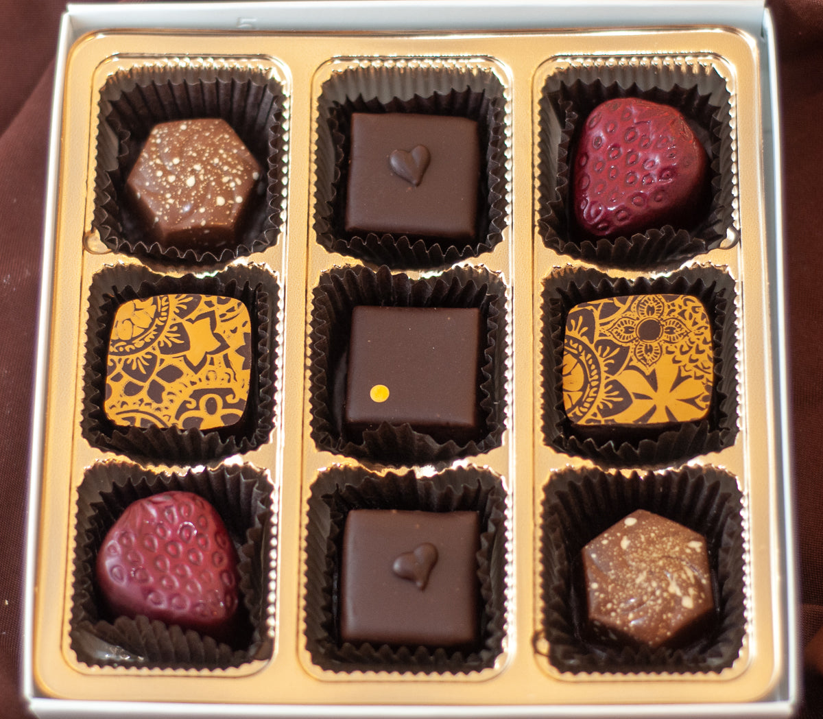 Fan Favorites 2020 overhead view — 9-piece box of TSC's most-popular bonbons with strawberry shapes, gold-patterned dark chocolate squares, and nut-topped pieces.
