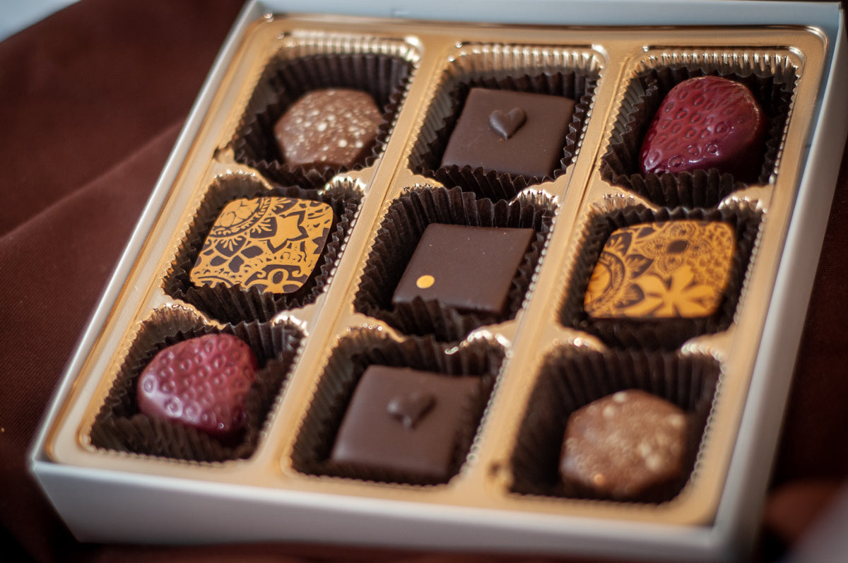 Fan Favorites 2020 9-piece chocolate box — assortment including strawberry-shaped bonbons, gold-patterned dark chocolate squares, and nut-topped pieces. Main image