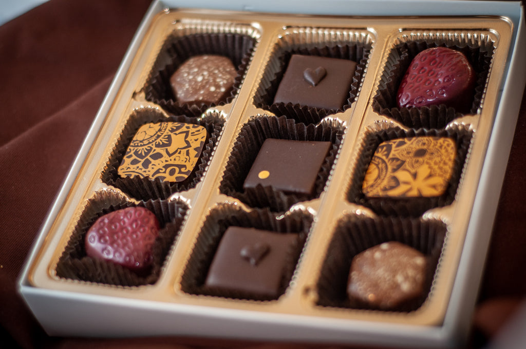 Fan Favorites 2020 9-piece chocolate box — assortment including strawberry-shaped bonbons, gold-patterned dark chocolate squares, and nut-topped pieces.