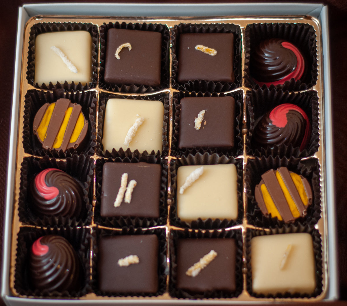 Fruitsy Tootsy assortment close-up showing the hand-painted fruit-themed bonbons with red, yellow, and orange accents.