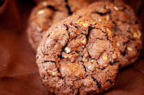 Flourless Crunchy Chocolate Walnut Cookies — dark chocolate cookies with visible walnut pieces and a cracked, crisp surface.