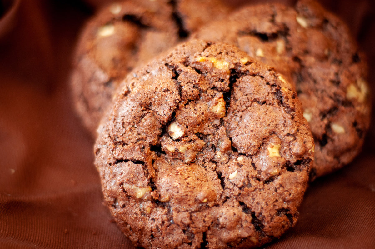 Flourless Crunchy Chocolate Walnut Cookies — dark chocolate cookies with visible walnut pieces and a cracked, crisp surface.