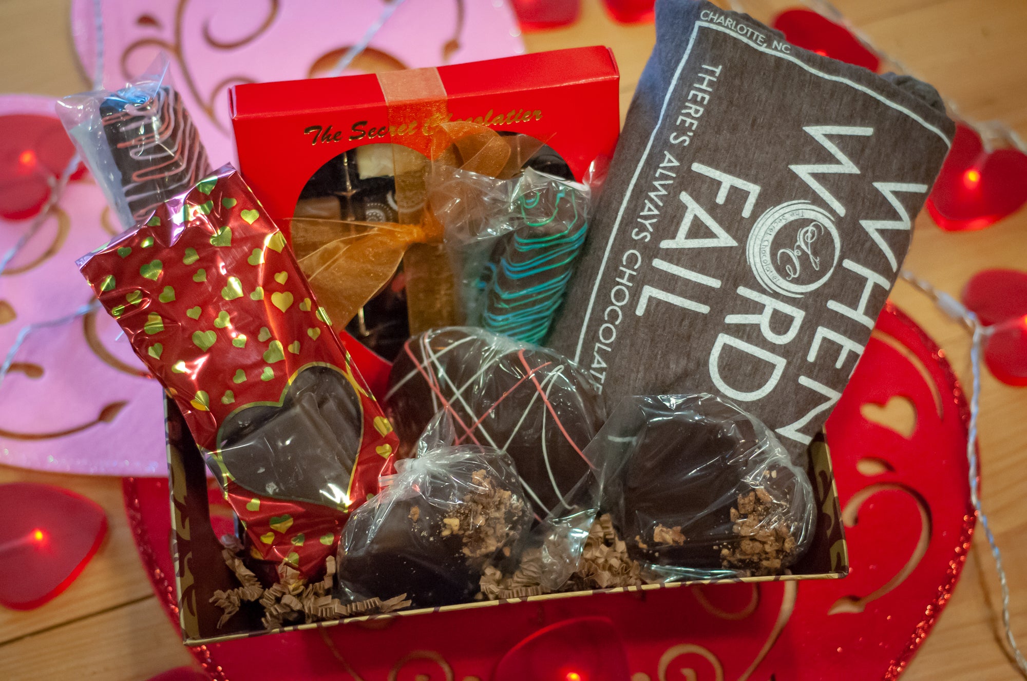 When Words Fail There's Always Chocolate gift box — Secret Chocolatier branded red box, 'When Words Fail' shirt, heart-shaped chocolates, and a chocolate-covered pretzel pop.