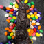 Upright dark chocolate Easter bunny surrounded by colorful jelly beans on a textured surface.