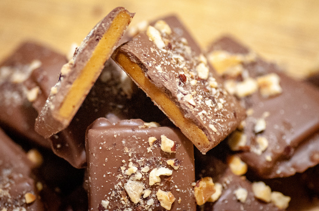 Milk Chocolate Hazelnut Butter Toffee broken into rough pieces with chopped hazelnuts across the milk chocolate.