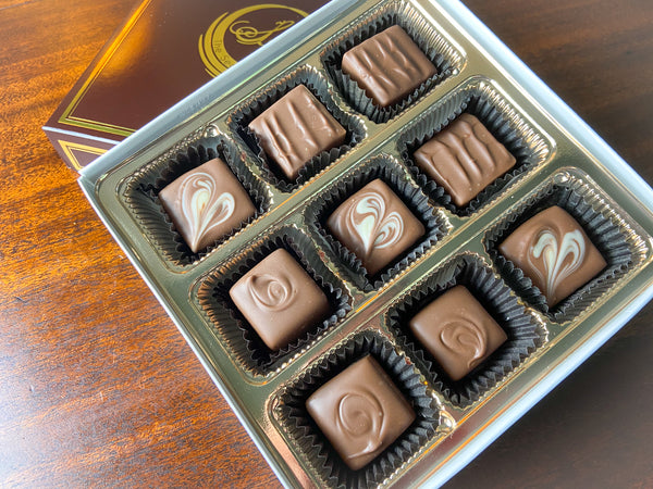 Nothing But Milk 9-piece chocolate box — milk chocolate truffles and bonbons with varied decorative pipings.