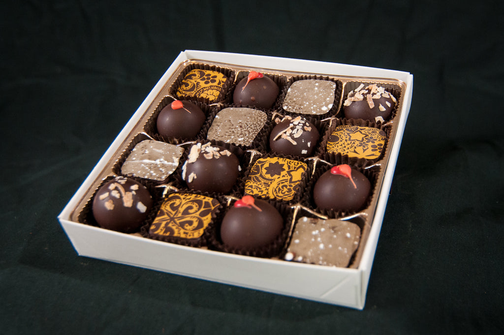 Seasonal Variety 16-piece chocolate box — assortment of truffles and bonbons with red dot accents, gold patterns, and various toppings.