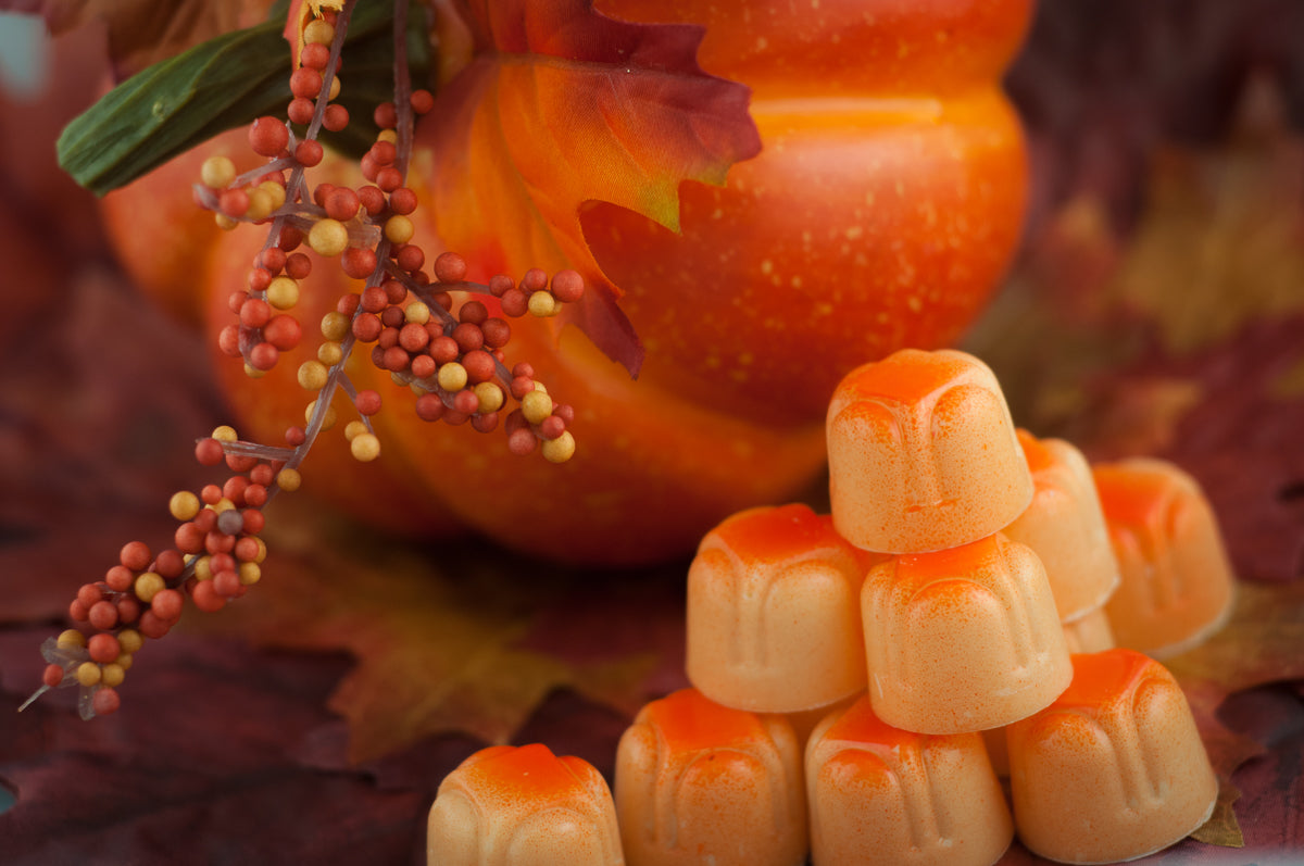 Fall Seasonal Variety — pyramid of orange pumpkin-shaped chocolates with a real pumpkin, autumn leaves, and berries.