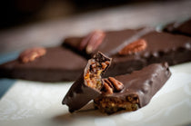 Dark chocolate Bourbon Pecan Pie Bites topped with pecan halves, one broken open to show the bourbon-pecan filling — one of the items featured in the Celebration Box sampler.