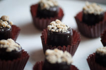 Peanut Caramel Cup — chocolate cup filled with caramel and topped with crushed peanuts, in a burgundy paper liner.