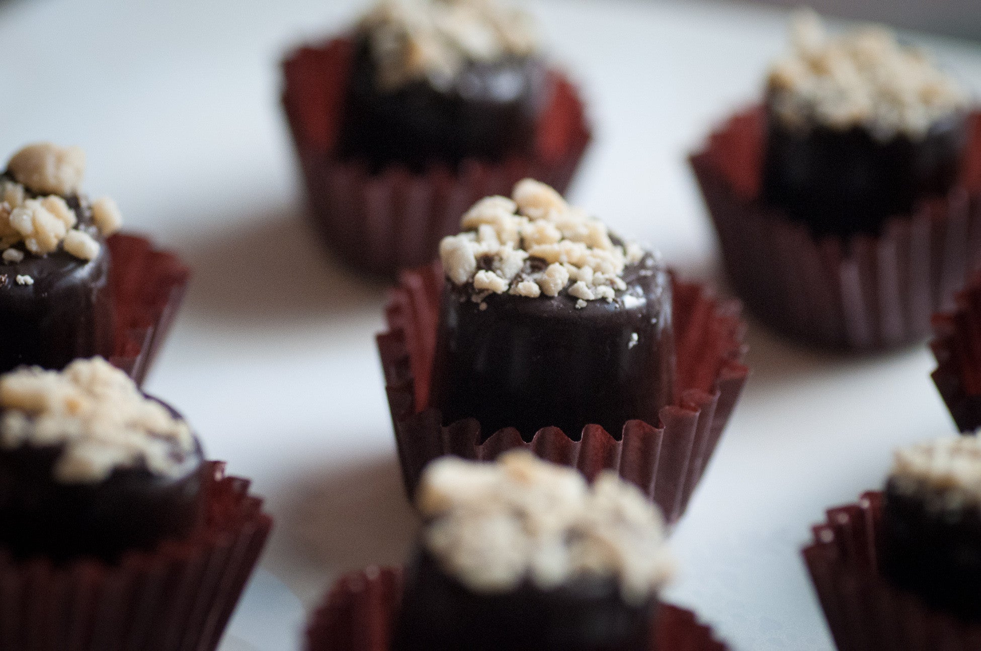 Peanut Caramel Cup — chocolate cup filled with caramel and topped with crushed peanuts, in a burgundy paper liner.
