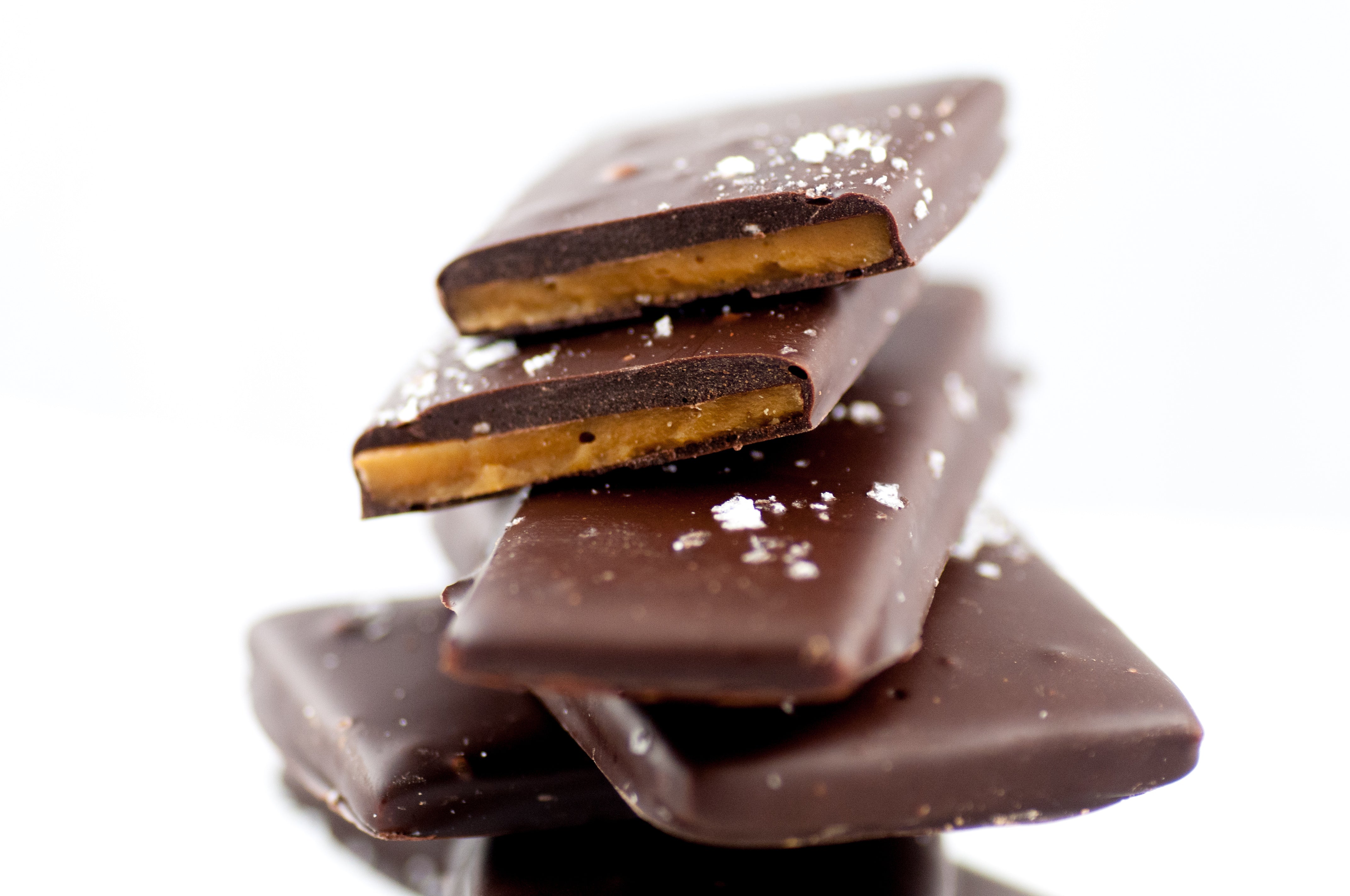 Stack of Sea Salt Chocolate Butter Toffee slabs, the buttery toffee visible beneath the dark chocolate-and-sea-salt finish. Main image