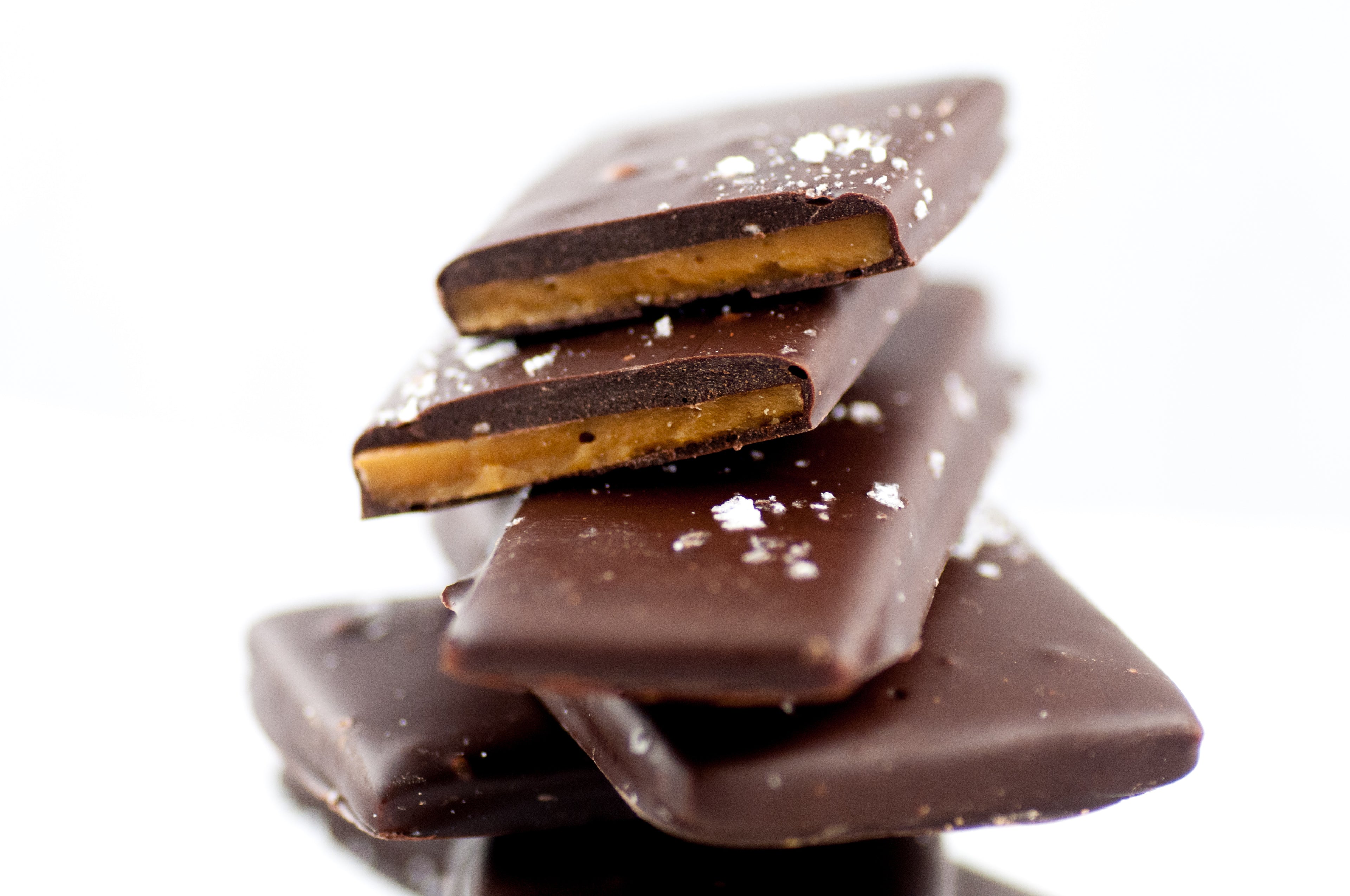Stack of Sea Salt Chocolate Butter Toffee slabs, the buttery toffee visible beneath the dark chocolate-and-sea-salt finish.