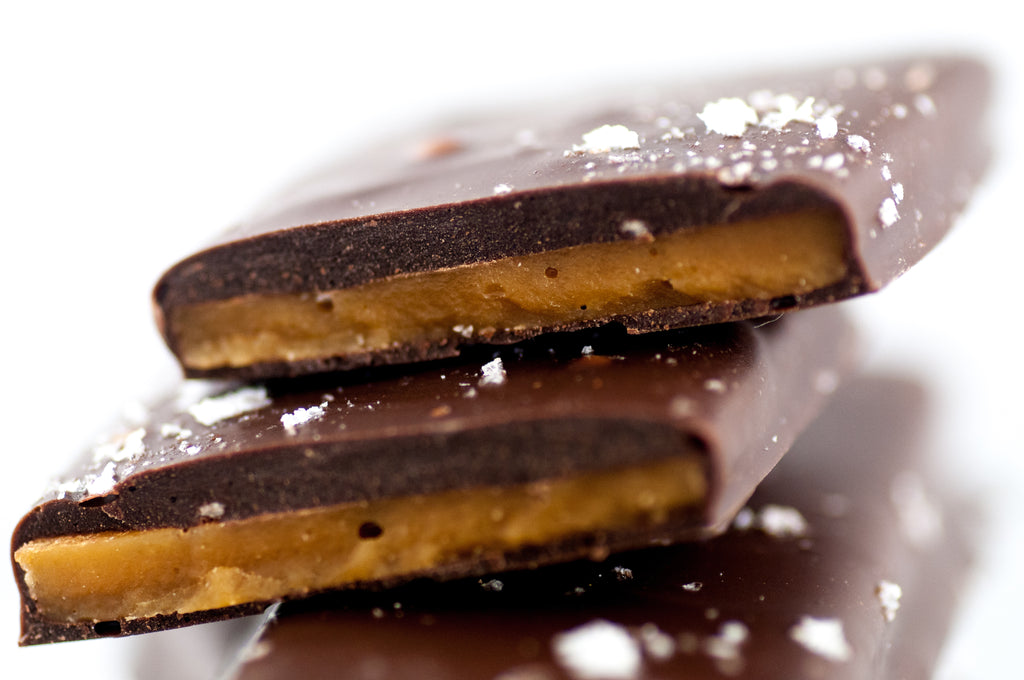 Sea Salt Chocolate Butter Toffee slabs at a side angle, flaked sea salt scattered across the dark chocolate.