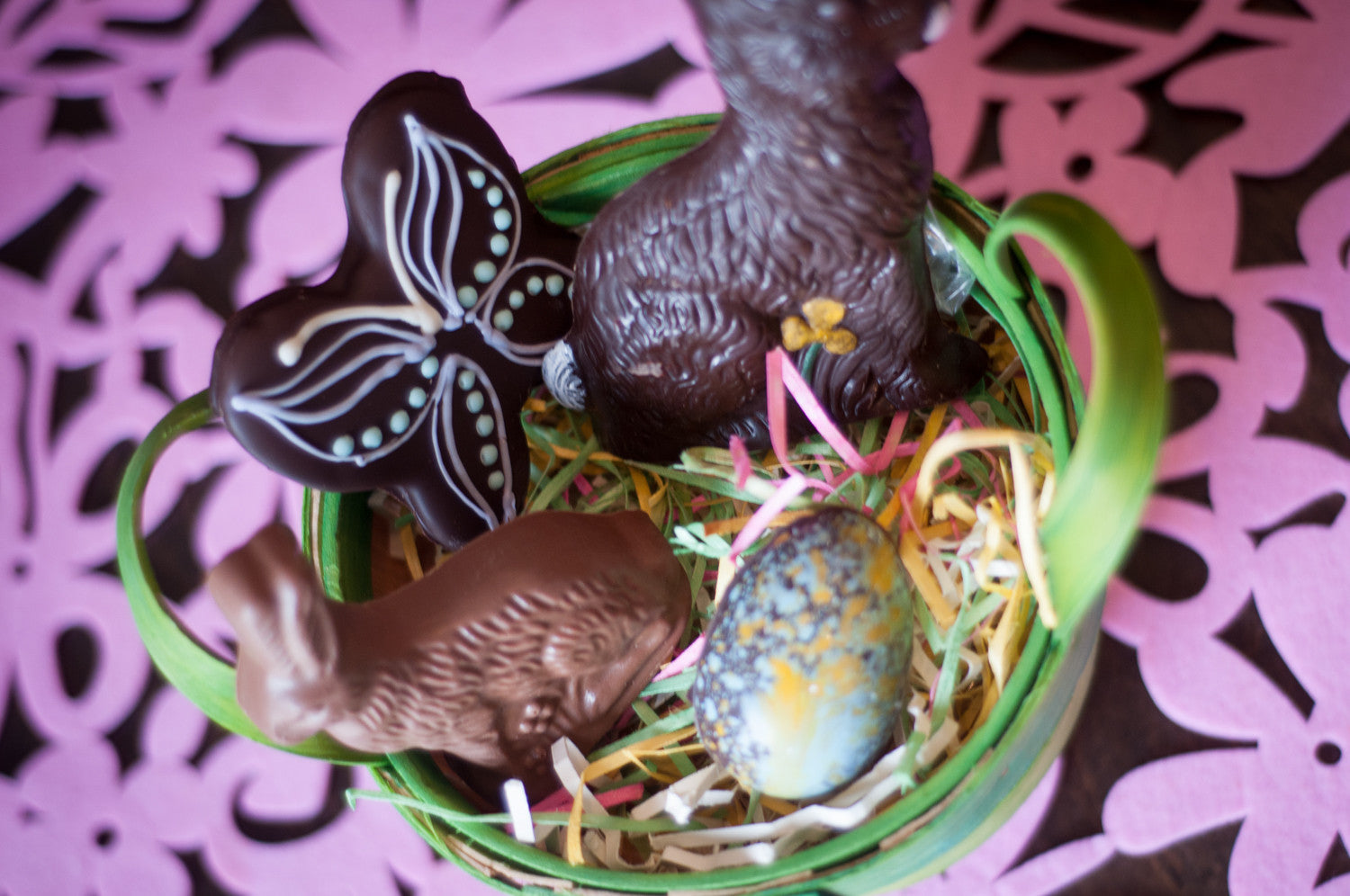 Small Chocolate Easter Basket from above — chocolate butterfly, milk and dark chocolate bunnies, and a hand-decorated egg in a green-edged basket.