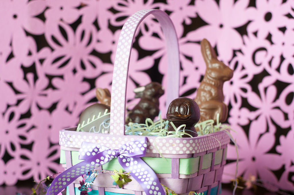 Large Chocolate Easter Basket — lavender wicker basket with milk and dark chocolate bunnies, a chocolate duckling, and a decorated chocolate egg in grass-like filler.