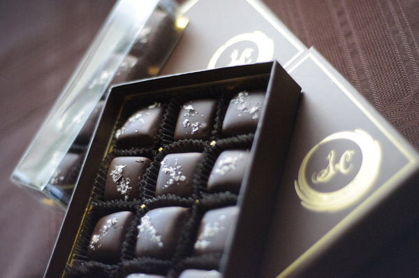 Dark Chocolate Caramels with Sea Salt arranged in a box, each pillow-shaped chocolate finished with flaked sea salt.