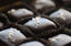 Dark Chocolate Caramels with Sea Salt — close-up of pillow-shaped chocolates topped with flaked sea salt in dark paper cups.